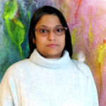 Person standing in front of a decorative background.